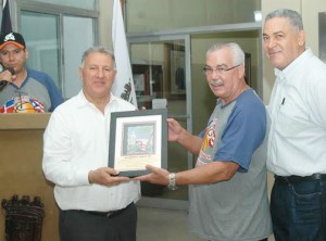 El presidente de la delegación Maxi-amigos de Puerto Rico, Tony Hiraldo, recibe un pergamino de reconocimiento de parte de Gilberto Serrule, alcalde de Santiago. 