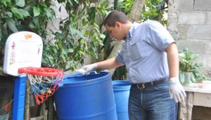 Víctor Fadul procede a echarle cloro a un tanque de agua.